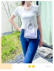 Détail d'un petit sac lilas à motif marguerites avec anse et bandoulière en cuir blanc