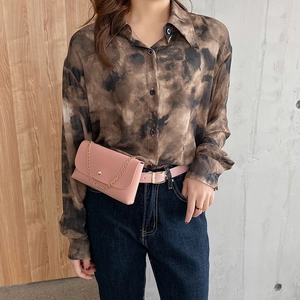 Pink leather belt bag with gold chain strap worn over minimalist beige outfit