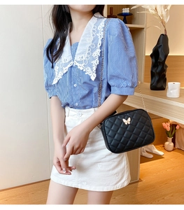 Detail of black quilted crossbody bag featuring a golden butterfly clasp and metal chain