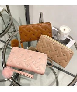 Detailed shot of quilted wallets with heart embroidery and fluffy pompom keychains
