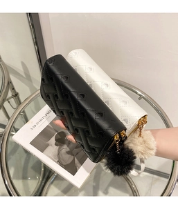 Close-up of long zip wallets with heart patterns and faux fur pompom charms