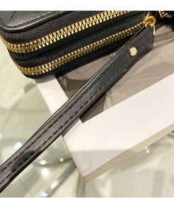 Close-up of black quilted leather wallet featuring double gold zippers and hand strap