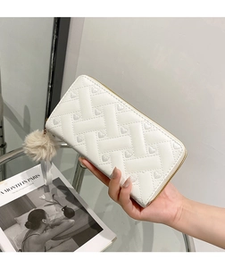 Detail of white PU leather wallet with quilted heart pattern and fur ball charm