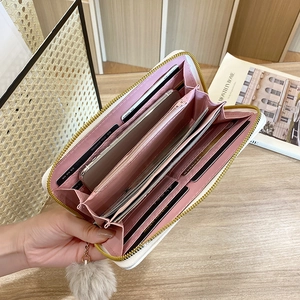White V-quilted long wallet with plush ball charm and organized card slots interior