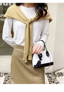 Détail d'un sac coquillage matelassé blanc avec bordure noire et bandoulière dorée