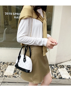 Détail du sac coquillage blanc matelassé avec bordure noire et chaîne dorée chic