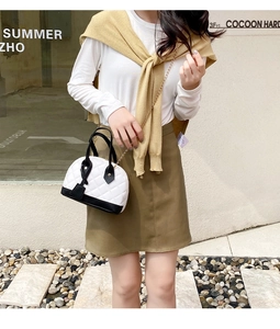 Sac coquille matelassé chic avec passepoil contrasté et chaîne dorée porté par un mannequin
