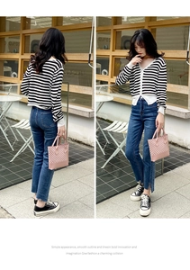 Detail shot of a trendy pink checkered handbag with classic striped cardigan and denim jeans