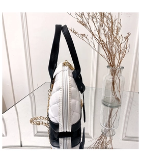 Vue détaillée du sac matelassé bicolore avec chaîne dorée sur surface miroir