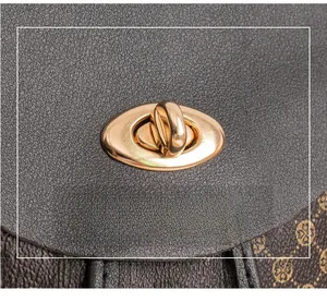Macro view of a golden metal swivel lock on a grey and brown printed leather handbag