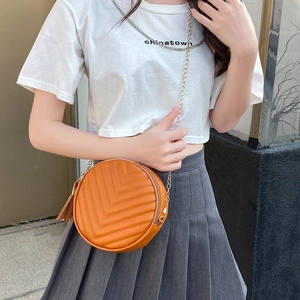 Orange quilted circular crossbody bag with gold chain strap and stylish tassel detail