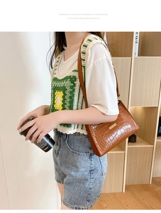 Close-up of brown crocodile pattern shoulder bag with a gold rectangular buckle clasp