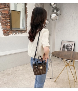 Back view of model wearing a geometric printed bucket bag with metal rivets and strap