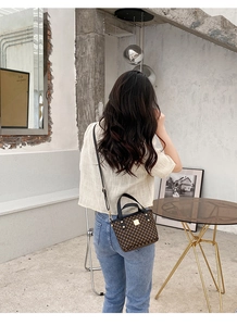 Detail shot of a compact printed bucket bag with gold rivets worn on shoulder