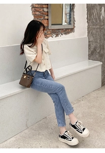 Outdoor street style view of a printed bucket bag with gold rivets and metallic clasp