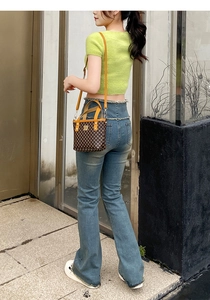 Detailed view of the checkered bucket bag with orange leather trim and metal rivets