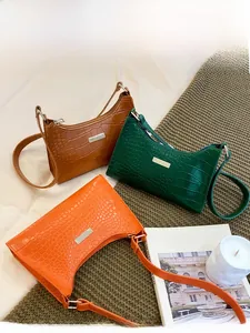 Detail shot of crocodile pattern baguette bags in orange, green, and brown colors
