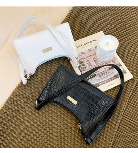 Detail of crocodile pattern baguette bags in black and white with gold hardware