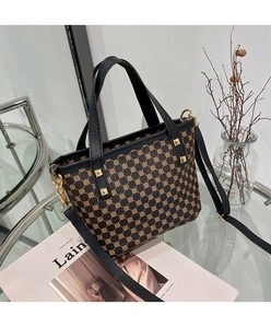Close-up of geometric printed bucket bag with gold rivets and black leather straps
