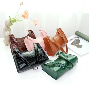 Flat lay of multiple crocodile pattern underarm bags in various colors on a stylized background