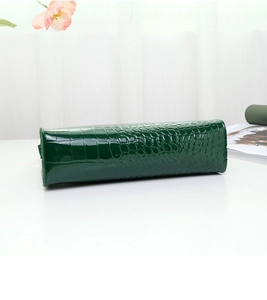 Detailed view of dark green crocodile texture leather on minimalist shoulder bag