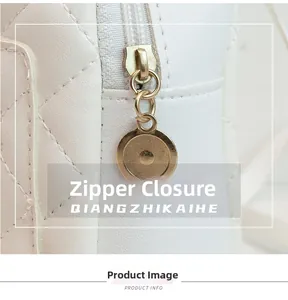 Detail of white quilted backpack featuring a gold round zipper pull and secure closure