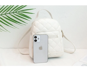 Detailed view of mini white quilted backpack with zipper pocket and phone for size reference