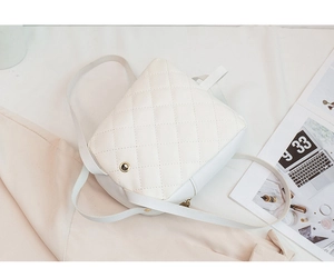 Detail of white quilted faux leather backpack with diamond stitching and metal eyelets
