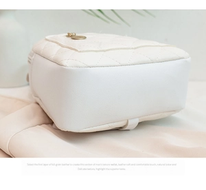 Detail of quilted leather mini backpack with fine stitching and circular metal zipper