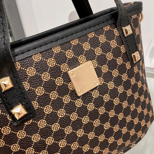 Brown leather bucket bag with floral print, black trim, and golden studs