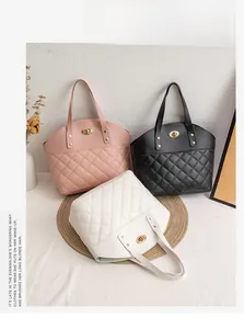 Detail of quilted tote bags in pink, black, and white with golden oval twist locks