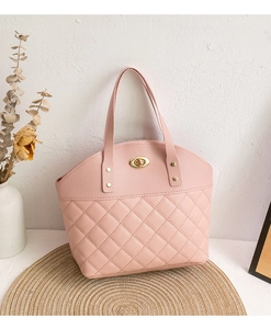 Detail view of pink quilted handbag with gold twist lock on a rustic woven mat