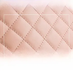 Macro detail of pink quilted faux leather fabric with precise diamond stitching texture