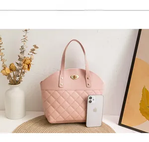 Close-up of light pink quilted handbag featuring gold metal turn-lock and stud details