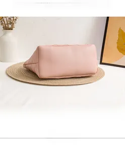 Detail view of pink quilted leather handbag with diamond pattern and side bucket structure
