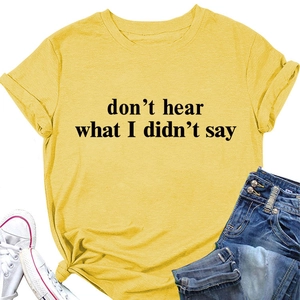 Dettaglio di una t-shirt giallo zenzero con slogan, orlo annodato e maniche risvoltate