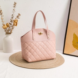 Elegant pink quilted handbag with gold twist lock on a rustic woven mat setting