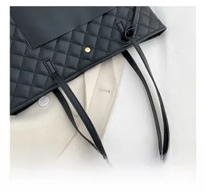 Detailed close-up of black quilted leather stitching and gold metal buckle on tote bag