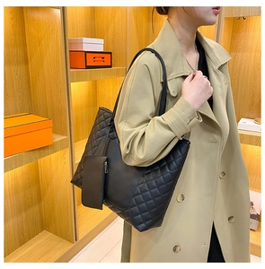 Detail of black quilted tote bag set featuring matching detachable pouch and shoulder strap
