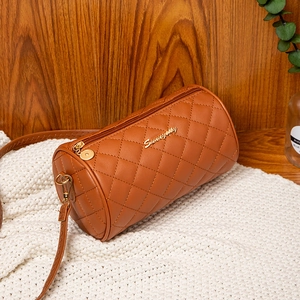 Brown quilted cylindrical shoulder bag with gold logo on a soft white knit surface