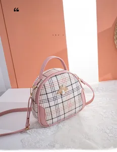 Detail of white plaid handbag featuring golden bee clasp and pink handle accents
