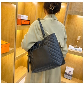 Quilted black tote bag with matching coin purse shown on a model's shoulder for size
