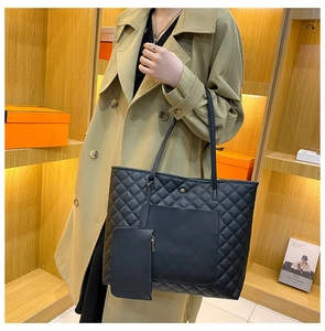 Detail of black quilted tote bag with matching pouch shown on a trench coat model