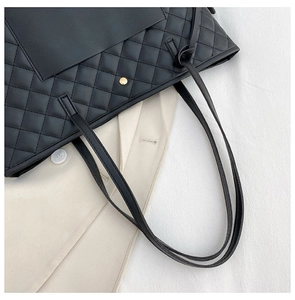 Close-up of quilted black tote bag featuring elegant gold hardware and leather texture