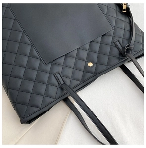 Detail of black quilted tote bag featuring gold magnetic snap and leather shoulder strap