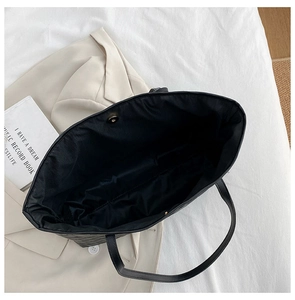 Close-up of black quilted tote bag showing spacious interior with metal magnetic closure