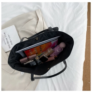 Spacious interior of black quilted tote bag showing organized daily essentials and tablet