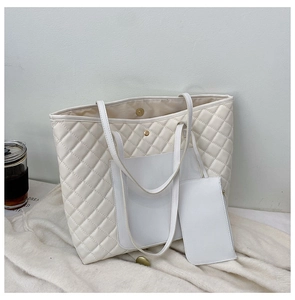 Close-up of white quilted tote bag with magnetic clasp and matching inner zipper pouch