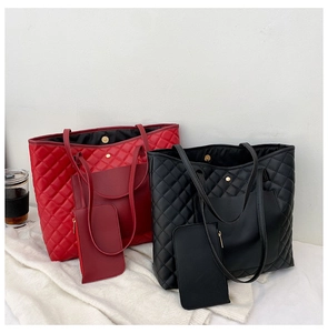 Detail view of red and black quilted tote bags with matching zipper pouches on white fabric