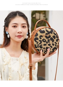 Dettaglio della borsa rotonda leopardata con manico in pelle e logo dorato in metallo